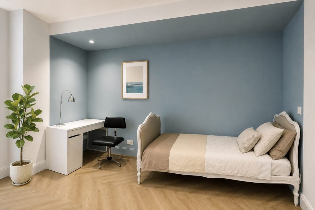 Chambre d’enfant bleu-gris avec lit et coin bureau réunis dans une alcôve, et sol effet bois.