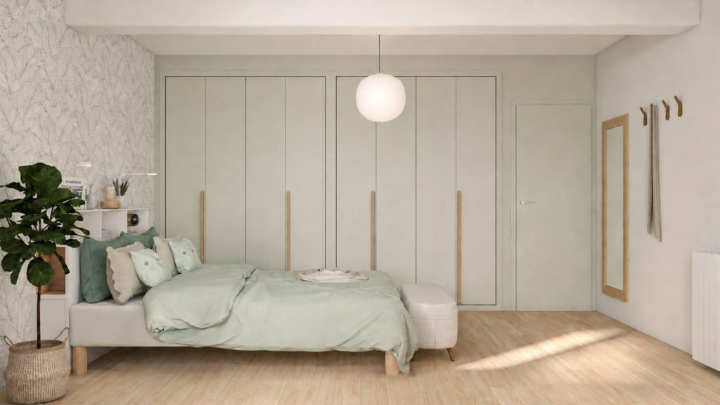 Vue latérale de la chambre parentale avec placards sur mesure vert sauge, longues poignées en bois et parquet clair.