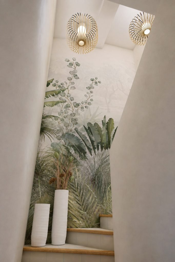 Vue depuis le bas de l’escalier avec papier peint panoramique végétal, puits de lumière et suspensions en bois et blanc.