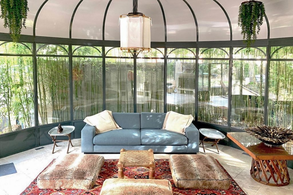 Salon avec canapé bleu, tapis oriental et verrière ancienne dans la maison rénovée à Croissy-sur-Seine.