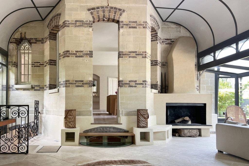 Salon avec cheminée, verrière ancienne et murs en briques dans la maison rénovée à Croissy-sur-Seine.