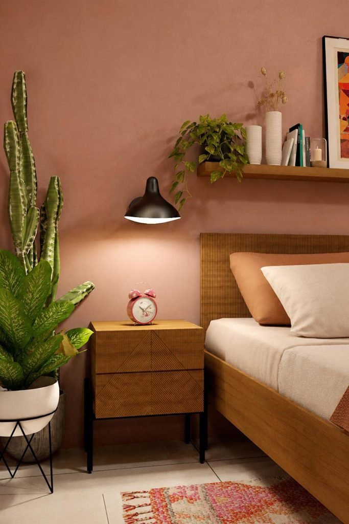 Détail de la chambre parentale avec lit en bois, mur rose terracotta et plantes vertes.