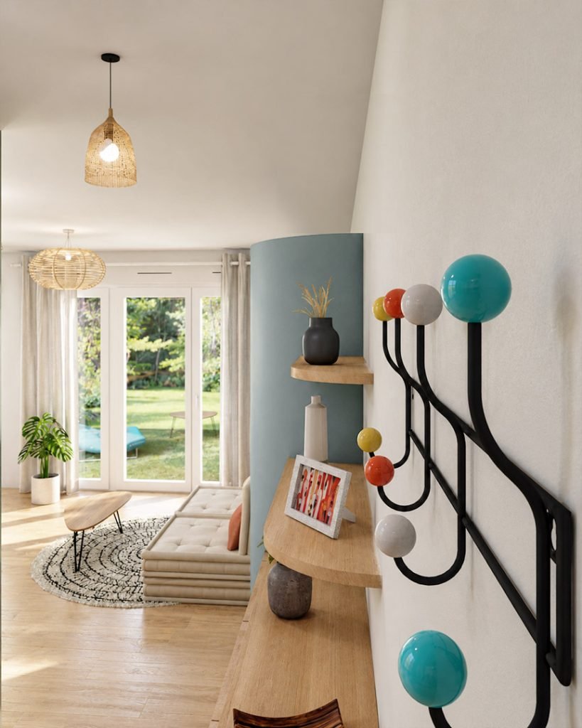 Entrée du studio avec patère colorée et rangements sur mesure en bois aux formes arrondies, ouverte sur le salon et le jardin.
