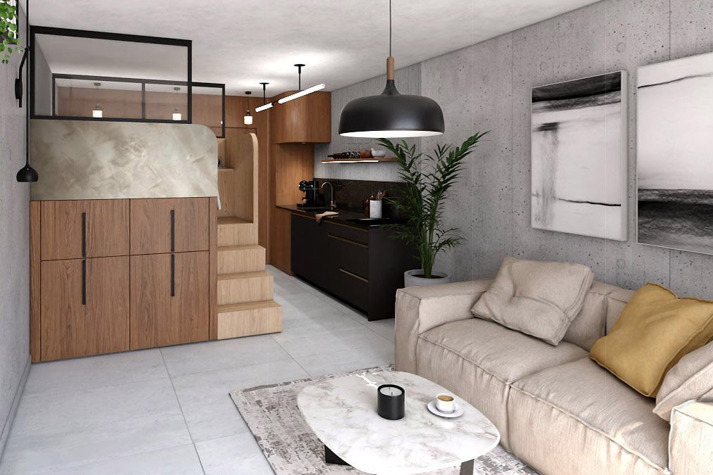 Espace de vie du studio avec salon, cuisine noire et cube multifonction en bois intégrant l’escalier et les rangements.