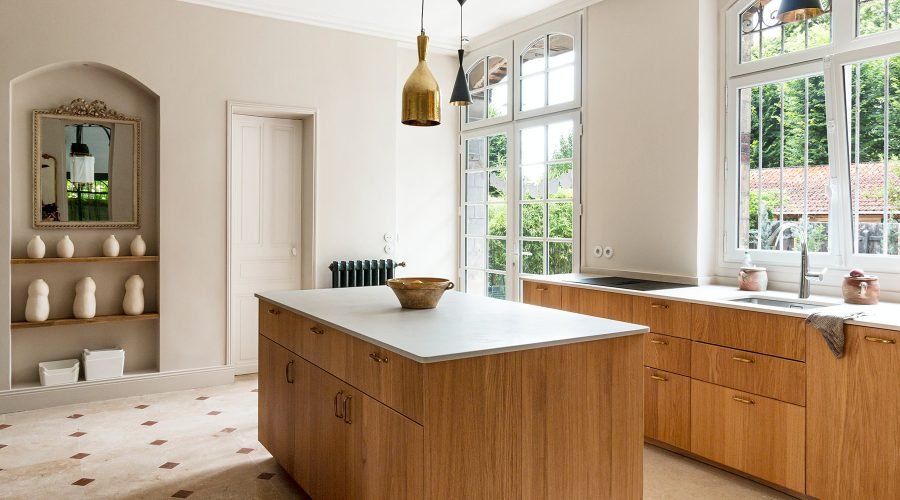 Cuisine rénovée en chêne avec îlot central et sol en travertin dans une maison ancienne à Croissy-sur-Seine.